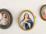 four miniature portraits of women in ornate frames hang on a wall