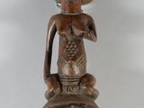 une petite statue représentant un homme assis sur un vase