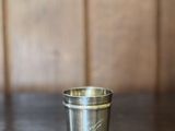 une petite tasse en métal posée sur une table en bois