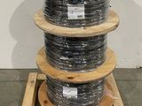 trois bobines de câble sont empilées sur une palette dans un entrepôt