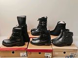 quatre paires de bottes noires sont posées sur des cartons, sur une table