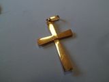 une croix en or sur une table blanche à côté d'une bouteille de vin
