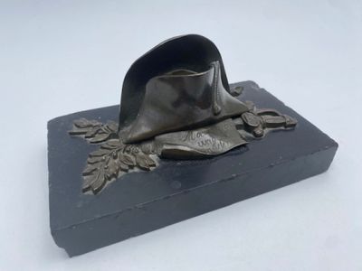 statue représentant un chapeau posé sur un socle orné de feuilles