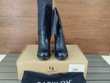 black leather high heeled boots on a box with a black bag