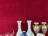 many vases and cups on a table with a red wall in the background