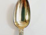 a silver spoon with a gold handle on a white surface