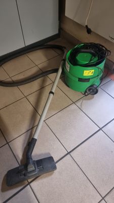 un aspirateur vert posé par terre à côté d'un seau vert