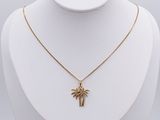 un collier en or avec un pendentif en forme de palmier sur un mannequin