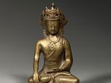 une statue en or représentant un Bouddha assis sur un socle blanc