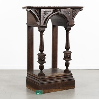une vieille table en bois avec un plateau sculpté et des colonnes