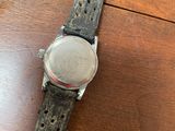 an old watch sitting on top of a wooden table on a wooden surface
