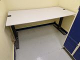un bureau blanc dans une petite pièce dont la porte est bleue