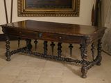 une table avec un plateau en bois dans une pièce où est accroché un tableau au mur