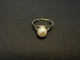 a close up of a pearl ring on a black surface
