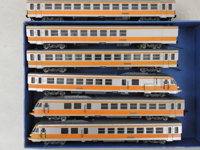 six trains dans une boîte bleue posée sur une surface blanche