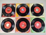 four black vinyl records on a white surface with a red label