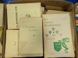 several books are stacked in a cardboard box on a table