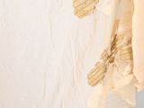 a close up of a white shirt with gold leaves on it