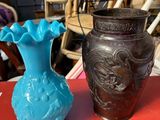 deux vases posés sur une table rouge, avec des chaises en arrière-plan