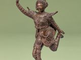bronze statue of a woman dancing on a pedestal against a green background