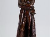 statue d'un homme en manteau et chapeau, les bras croisés