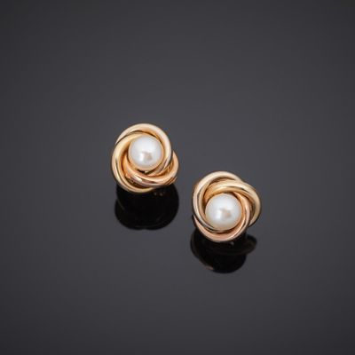 a pair of gold and pearl earrings on a black surface