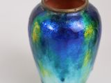 a blue and green vase sitting on a white surface