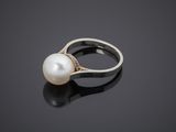 a white pearl and diamond ring on a black surface
