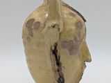 a brown vase with a face on it on a white surface