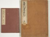 an old book sitting on top of a white table next to a brown book