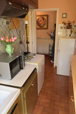 une femme debout dans une cuisine, près d'un évier et d'un micro-ondes