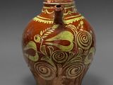 une image représentant un vase marron et vert posé sur une surface grise