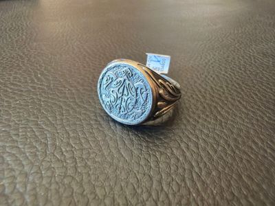 un gros plan d'une bague en argent posée sur une surface en cuir marron