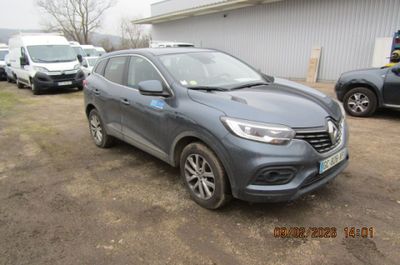 La voiture grise est garée devant un immeuble, avec d'autres voitures en arrière-plan.