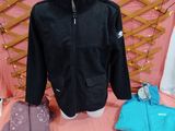 une veste noire et une veste bleue posées sur un lit rose