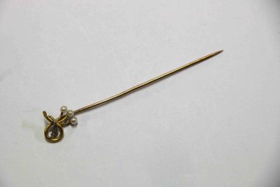 un gros plan d'une épingle en métal ornée d'une perle