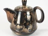 a small teapot with a handle on a white surface