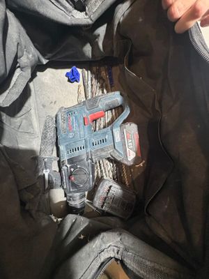 a person holding a corded drill in a bag