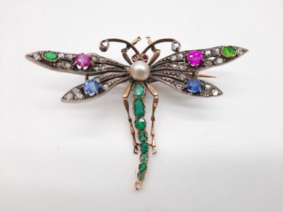 un gros plan d'une broche en forme de libellule ornée de pierres multicolores