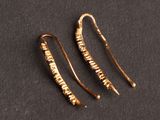 a pair of gold earrings on a black surface