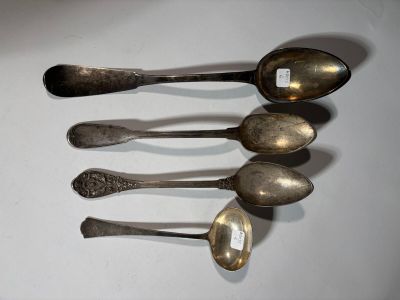 five silver spoons are lined up on a white surface
