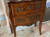 a small wooden chest of drawers on a marble floor