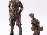 two bronze figurines of a boy and a dog on a rock
