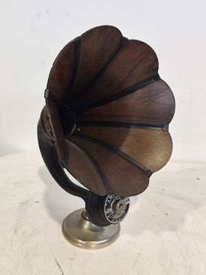 un petit gramophone en bois posé sur un support, lui-même posé sur une table