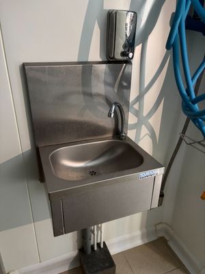 un lavabo en acier inoxydable dans une salle de bains, avec un tuyau bleu
