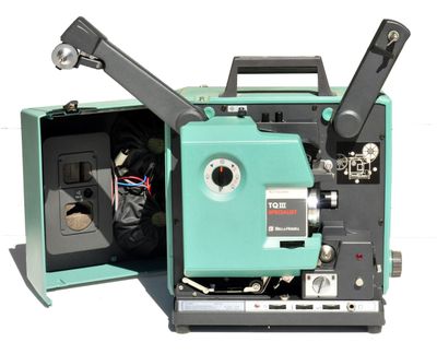 un vieux projecteur de cinéma posé, ouvert, sur une surface blanche