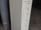 a tall white cabinet with five drawers in a garage