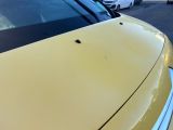 a yellow car parked in a parking lot with other cars in the background