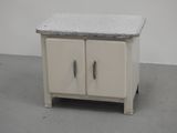 a small white cabinet with a granite top on a gray floor