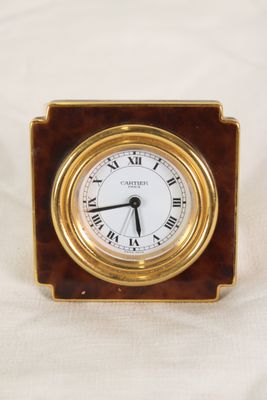 une petite horloge avec des chiffres romains posée sur une table